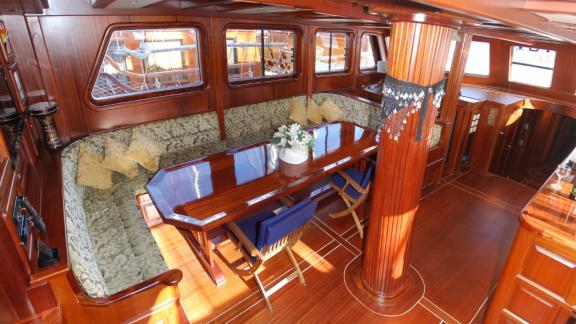 A stylish saloon on the gulet Sahinoğlu with a large dining table, comfortable seating and elegant wood panelling.